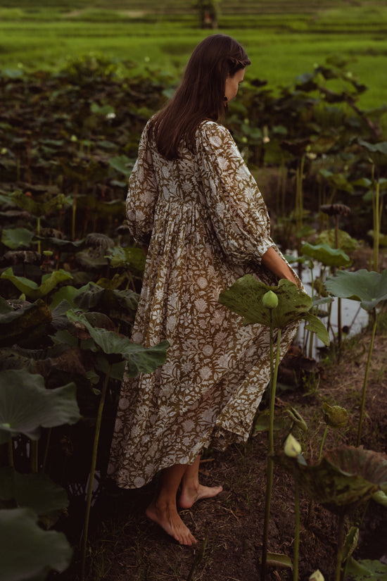 Daughters of India Kyra Maxi Dress in Olive — back view walking through lotus pond, billowed sleeves, gathered waist