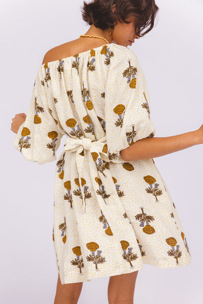 Dahlia Mini Dress Marigold — back view showing tie-waist detail and off-shoulder back neckline, white linen with golden marigold hand block print, billowy sleeve drape, artisan ethical dress | Daughters of India