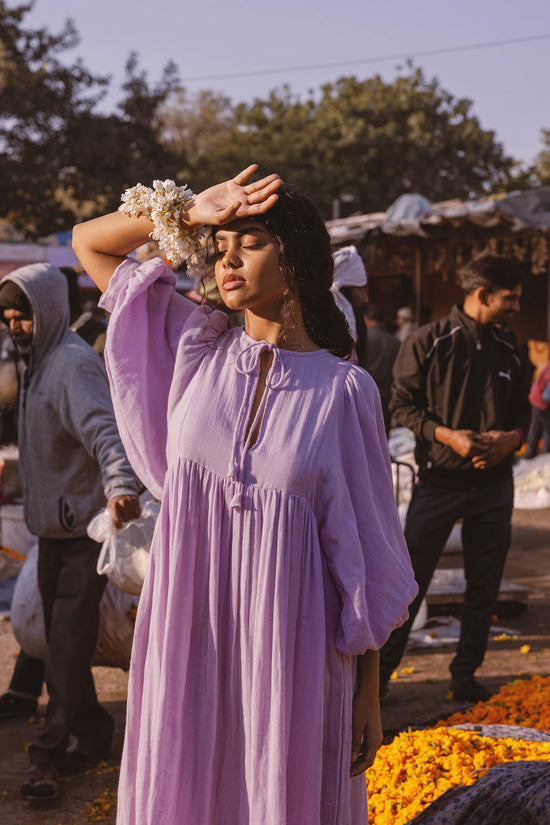 Daughters of India Kyra Midi Dress in Lilac Gauze — close-up at flower market, hand on forehead, billowed sleeves