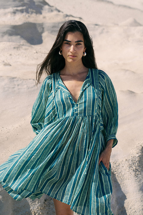 Woman wearing a green and white striped dress on a sandy background