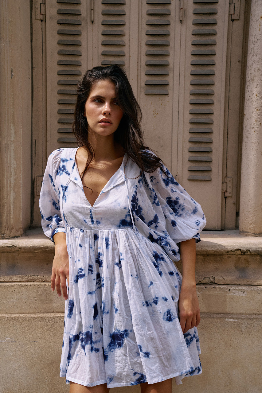 Kyra Mini Dress Deep Sea — back view against stone wall, deep sea shibori tie-dye cotton mini dress showing back neckline detail, European building facade | Daughters of India