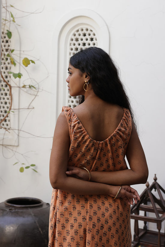 Sundress Midi Peach — model on beach rocks, scenic coastal backdrop, full length lifestyle portrait, hand block print peach cotton midi dress, sustainable Indian fashion | Daughters of India